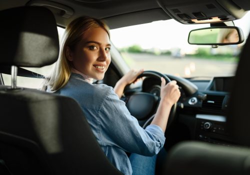 Smiling female student in the car, driving school